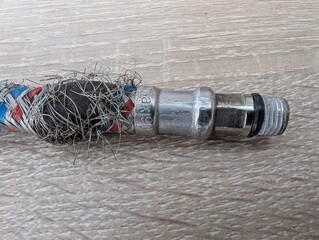 Damaged hose connector reveals wear and tear from years of use outdoors and its fascinating texture on a wooden surface