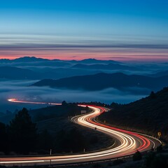 An atmospheric shot of a road carving through misty mountains, captured with the dynamic effect of long exposure light trails.