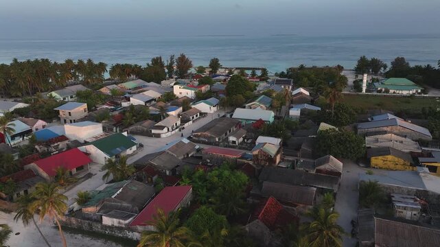 Aerial view of Naavaidhoo, where colorful houses contrast with the green mosque and the turquoise ocean, creating a vibrant island scene, Naavaidhoo, Haa Dhaalu City, Maldives.