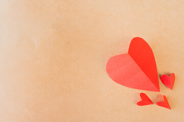 Two paper hearts and smaller heart shapes on a beige surface, love concept.