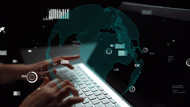 Close-up of hands typing on a laptop keyboard with an overlay of a globe and data visualizations, representing global connectivity and digital innovation in a dark environment. Xenic
