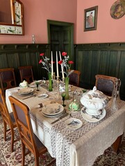 Vintage dining room table set for guests in Art Nouveau style. Elegant antique dishes, green glass...