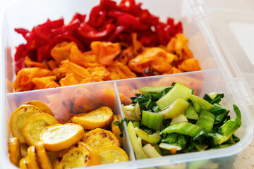 Healthy meal prep: colorful sliced bell peppers with zucchini and bok choy in container