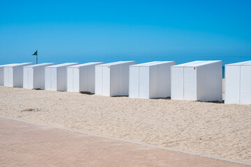 Row oof white beach cabines at the seaside in Koksijde bad, West Flanders, Belgium
