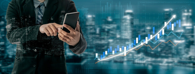 A businessman in a suit engages with a smartphone while viewing a growing financial graph overlayed...