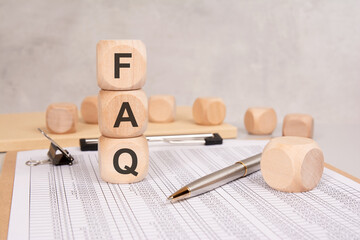 Stacked wooden cubes forming FAQ on financial data sheet