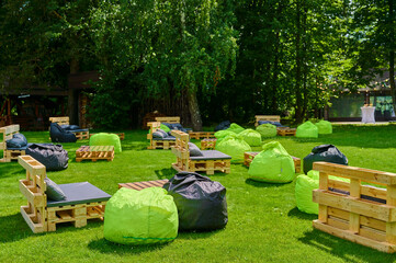 Lush outdoor event space with wooden pallet seating and bright green bean bag chairs on vibrant...