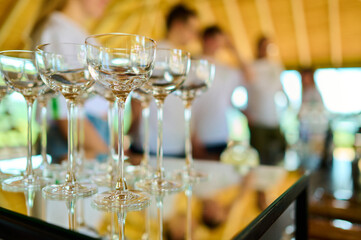 Elegant glasses of champagne on a reflective surface in a warmly lit indoor setting, with blurred guests and wooden decor in background, evoking celebration or social event atmosphere