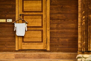 Interior of a rustic wooden cabin showcasing a wooden door with a towel hanging on a hook,...