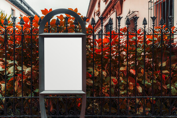 Vertical blank billboard mockup with elegant black iron frame placed in front of an ornate wrought iron fence and vibrant red foliage, with classical building facade blurred in the background