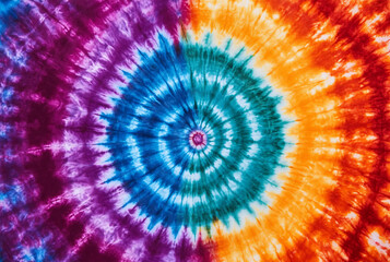 Vibrant tie dye spiral pattern in purple blue orange and red fabric textile
