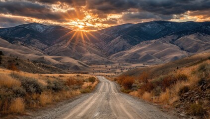 A dirt road winds through a valley at sunset.