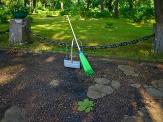 Fototapeta premium Broom and Dustpan in Park on a Sunny Day. Ideal for concepts related to public space maintenance, cleanliness, or gardening.