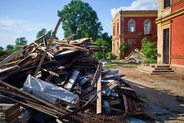 Demolition Debris near Abandoned Red Brick Building. Pile of wooden construction debris and old window frames in front of an abandoned red brick building.