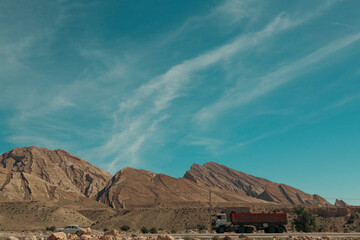 Layered rock formations and arid mountain slopes in Hormozgan, Iran, revealing striking geological textures beneath a clear blue sky.	