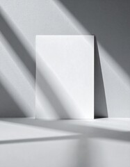 Minimalist White Paper Mockup on Gray Wall with Geometric Light and Shadows