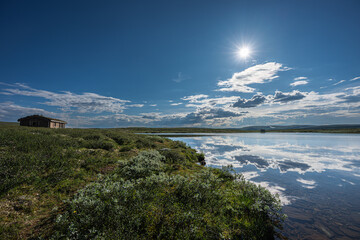 Summer in Norway, a highland lake and a lakeside mountain hut, the majestic summer sky and clouds...