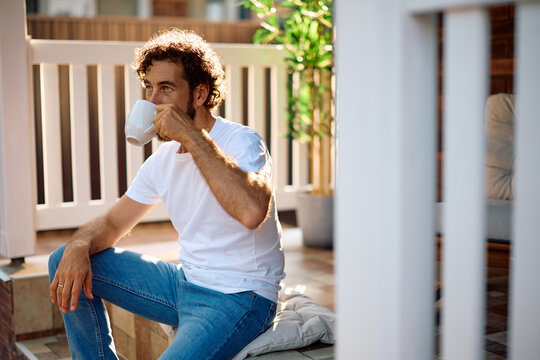 Mid adult man drinking morning coffee on porch.