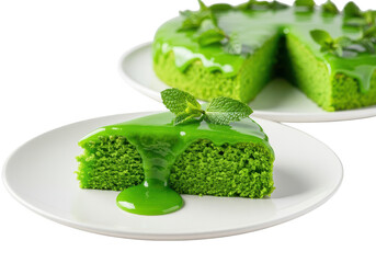 A slice of green cake with glaze and mint on a plate with another cake in the background on white on transparent background