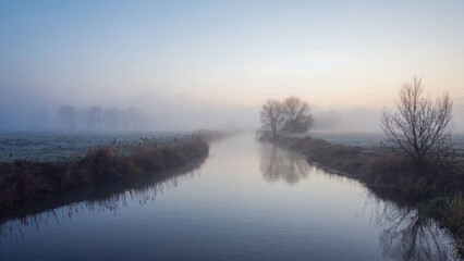 River bend disappearing into foggy horizon, soft gradient light and faded detail.