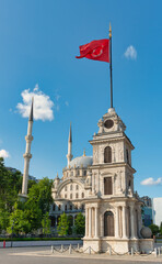 Fototapeta premium Tophane Clock Tower with Turkish flag, and Nusretiye Mosque under blue sky in Istanbul, Turkey