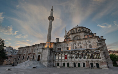 Laleli Mosque, Turkish: Laleli Camii, Istanbul, Turkey. Grand Ottoman architecture with a towering minaret and dome, captured at dusk under a soft, cloudy sky. Historic landmark.