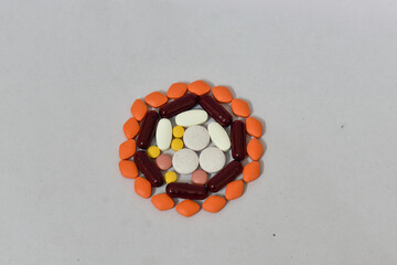 A symmetrical arrangement of various colorful pills and capsules on a white background. Medicine...