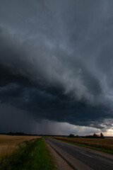 WEATHER Vertical Picture Dramatic black rain clouds over fields and country road