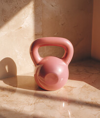 Pink kettlebell on a beige background under the summer sunlight	