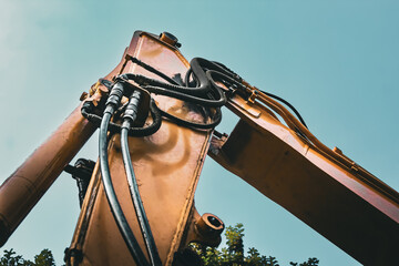 looking up at the arm and hydraulics of an excavator isolated against the sky construction...