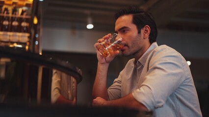 Sitting smart man drinking alone of cocktail Old fashioned waiting friends or couple at bokeh lighting at luxurious beverage counter nightclub at pub and restaurant on Friday meeting night. Vinosity.