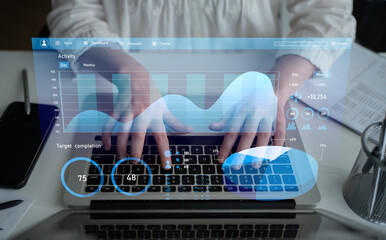 Person typing on laptop with digital data graphics overlay, representing business analytics and productivity in a modern office environment. Impute