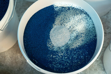 Production of decorative plaster at the factory. Materials for repair and decoration. Closeup of blue decorative plaster mixture in a bowl showcasing texture and contrast.