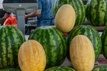 Watermelons and melons at the market. A colorful array of fresh melons and watermelons. Melons and watermelons in a lively market atmosphere. A colorful array of fresh melons and watermelons.