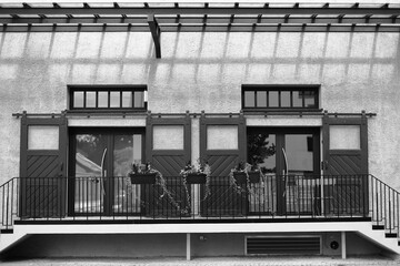 modern facade with dark doors, symmetrical architecture, flower boxes on railing, beige textured...