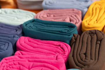 Colorful rolled fabric textiles arranged in a vibrant display showcasing various hues and textures