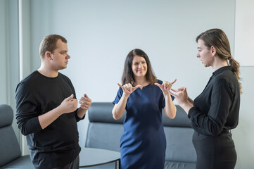 Caucasian woman teaching sign language to man and woman. 