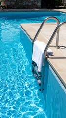 Obraz premium Swimming Pool with Steel Ladder and Clean Water with White Towel in Summer