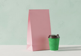 Pink paper bag and green coffee cup on a light background