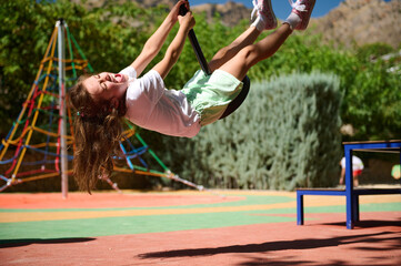 Child Swinging Happily on Playground Equipment During Summer Day