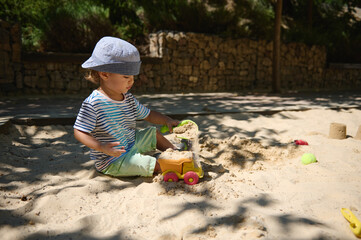 Young Child Enjoying a Summer Day Building Sand Castles in Playground