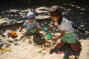 Children Playing Joyfully in a Sandbox on a Bright Summer Day