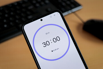 Phone timer white 30-minute stopwatch to study with pomodoro method on laptop keyboard, study business background