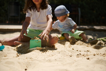 Kids Playing Together in a Sunny Sandbox During a Summer Day