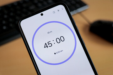A phone with a black and white 45-minute timer to study with pomodoro method on laptop keyboard, study business background