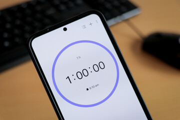 Phone white 1 hour timer to study with pomodoro method on laptop keyboard, study business background