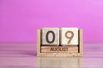 Wooden calendar showing the ninth of august, on a pink background