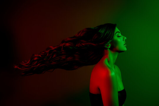 Portrait of attractive young lady model profile fluttering hair isolated multicolor red green neon effect background
