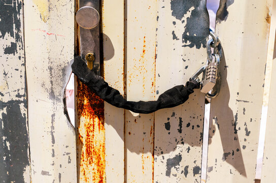 Mechanical gate code lock with numeric dials mounted on weathered metal gate