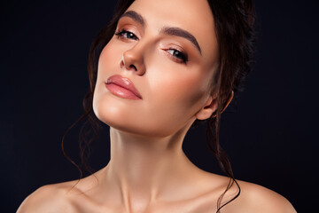 Portrait of a young brunette woman with elegant makeup and hairstyle on a dark background